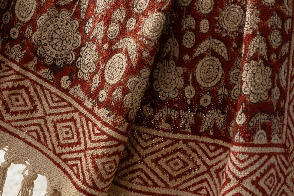 Close up of a Bagru madder red medallion hand block printed cotton throw with diamond border and fringe